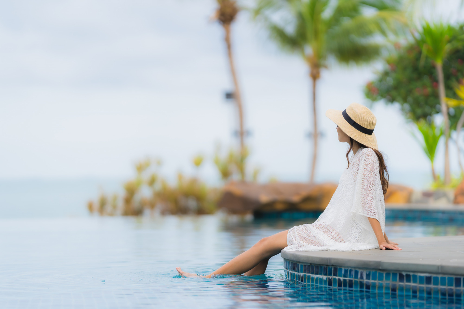 A girl sitting near a swimming pool with a beautiful view of a Sri Lankan hotel, highlighting Sri Lanka tourism.